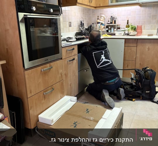אדם עובד במטבח עם ארגז כלים ומכשירים